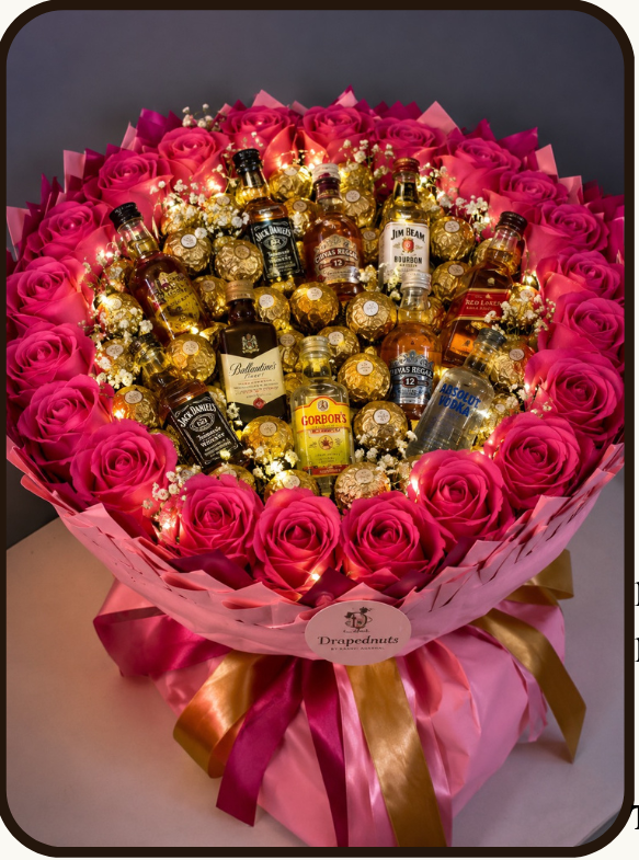 A luxury chocolate and rose bouquet gift set from Draped Nuts, featuring a circular arrangement of pink roses and assorted chocolates including Jägermeister, Ballantine's, Indri, and Bacardi. The image includes an 'What's Inside' list, product details, and pricing on a light beige background.