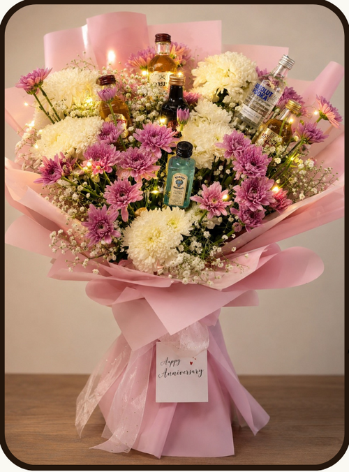 A floral gift bouquet arrangement with small liquor bottles tucked into pink wrapping, shown on a beige promotional graphic. The top displays the brand name Drapednuts, a product code MB2025, an 'What's Inside' list, and the product title 'Classic Spirit Symphony' with a price of ₹10499.