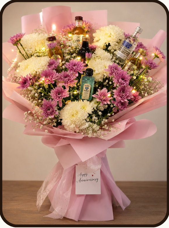 A floral gift bouquet arrangement with small liquor bottles tucked into pink wrapping, shown on a beige promotional graphic. The top displays the brand name Drapednuts, a product code MB2025, an 'What's Inside' list, and the product title 'Classic Spirit Symphony' with a price of ₹10499.