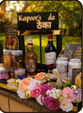 Promotional graphic for a Drapednuts 'The Celebration Crate' gift bundle, showing a decorated bar setup with various snacks, drinks, and flowers, alongside a list of what's inside and the price of ₹14999.
