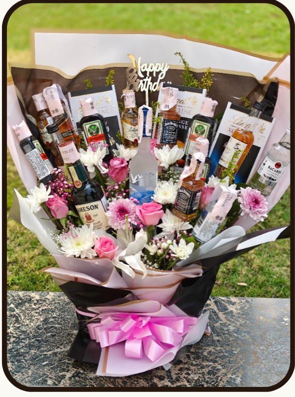 A promotional product listing for a 'Birthday Buzz Luxe' gift set by DrapedNuts. The image features a central photo of a 18-piece gourmet gift basket filled with chocolates, biscuits, and a pink wrapped bouquet, set against a cream-colored background with a product list and price of ₹14999.